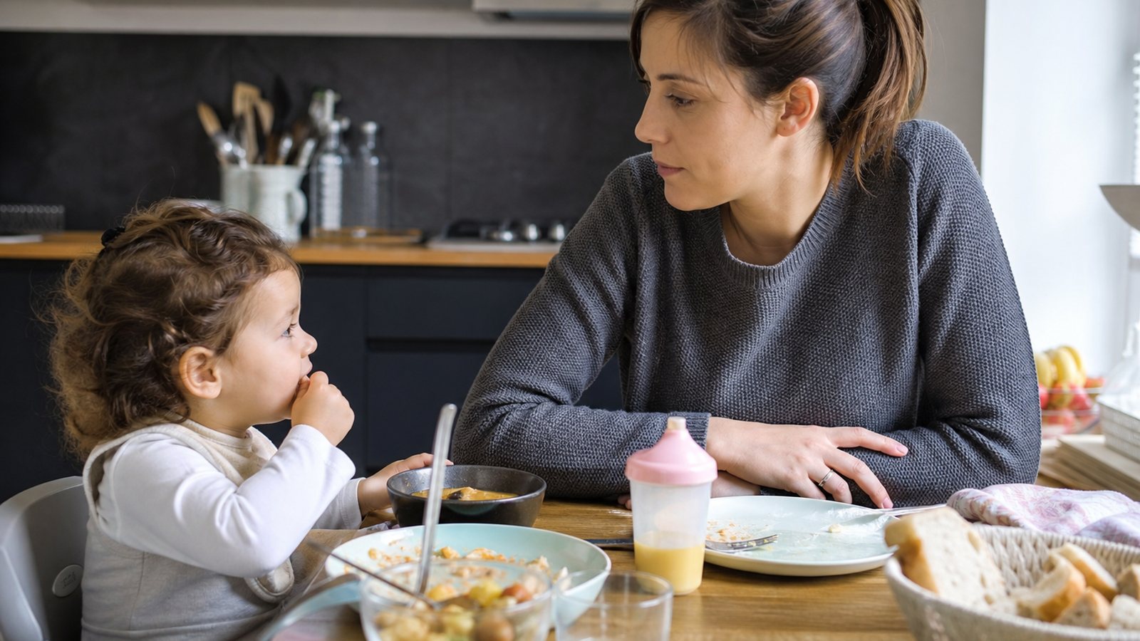 Garde d'enfants préparant le repas d'un jeune enfant dans la cuisine familiale
